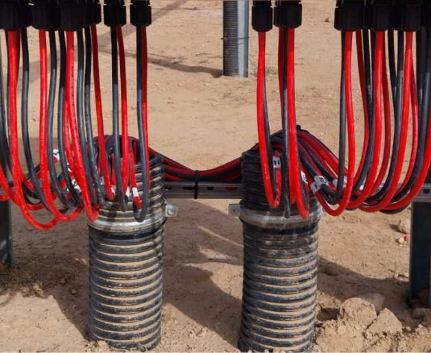 Gestão e organização de cabos elétricos em corrente contínua (DC) sob estrutura de central fotovoltaica, com conectores padronizados, amarração adequada e controlo de curvaturas.